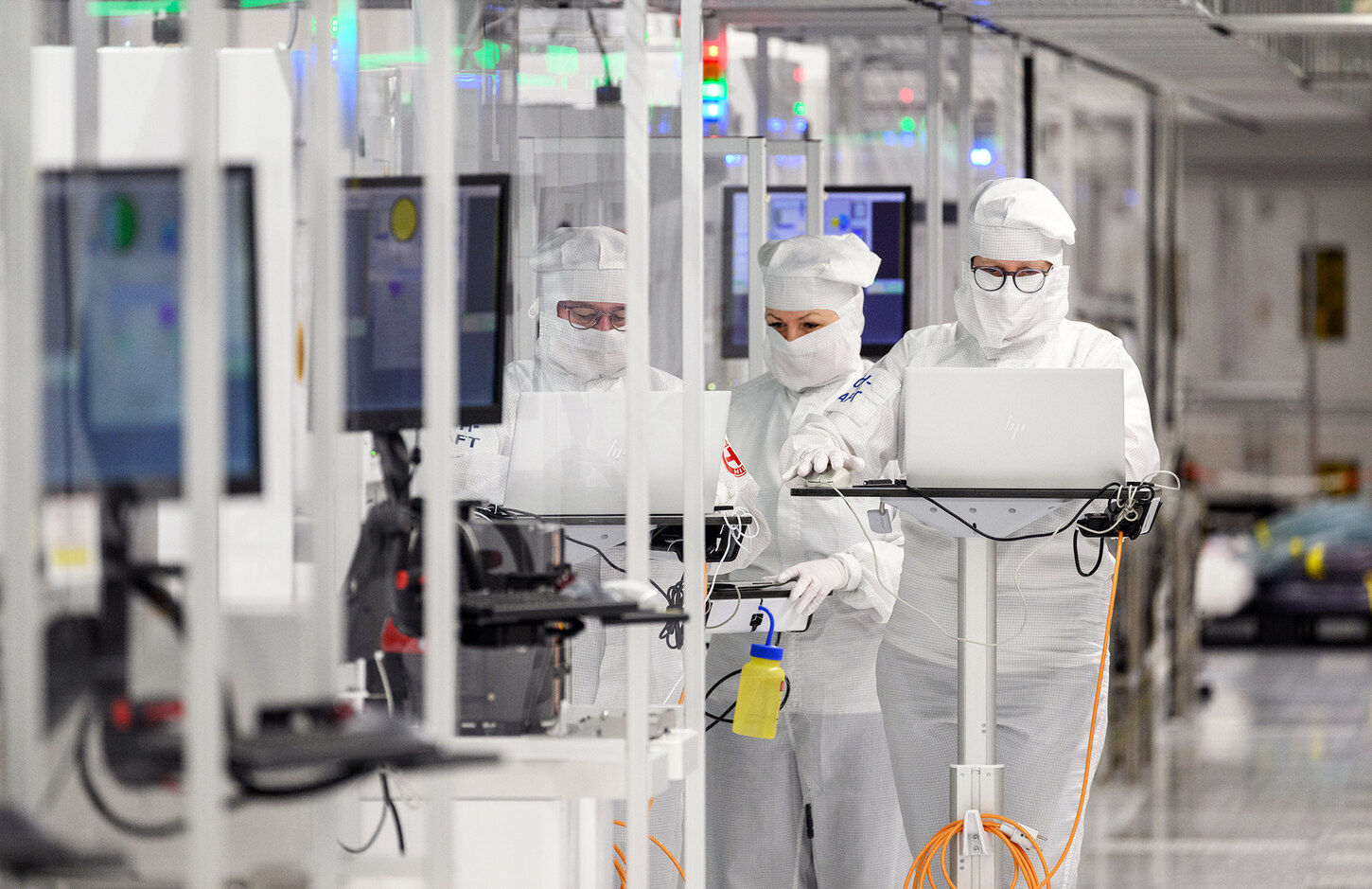 Zwei Frauen arbeiten in Schutzanzügen in einem Reinraum.