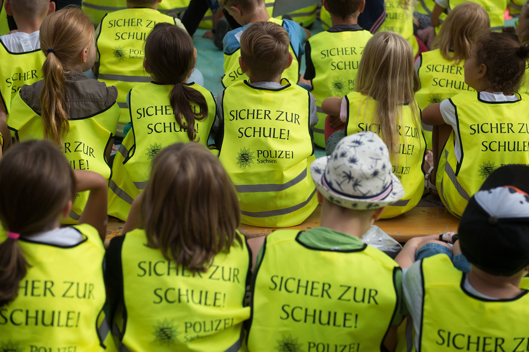 Kinder sitzen mit einer Warnweste zusammen.