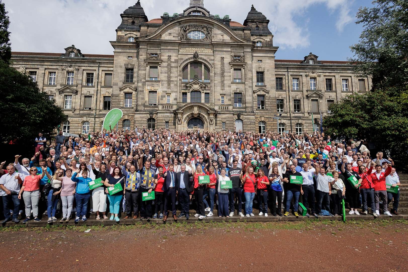 Viele Personen stehen vor einem Gebäude.